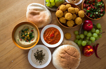 Traditional food of Israel on dark grey background with copy space. Colorful authentic meals top view photo: plate of hummus, falafels, salad, pita bread and tahini sauce. 
