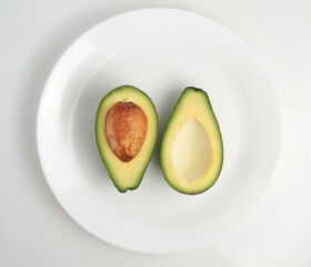 Two slices of avocado on a plate on a white background.Top view