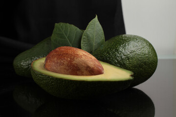 Fresh avocado slices with leaves. avocados reflected on a black background. Side view.
