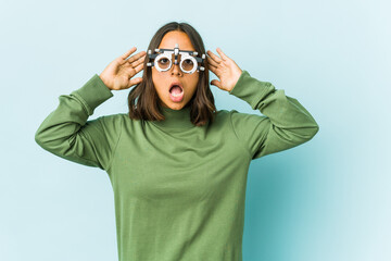 Young oculist latin woman over isolated background