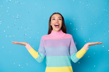 Photo of astonished girl look copyspace confetti air fly fall hold hand wear pullover isolated blue...