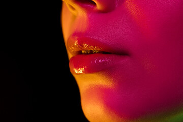 Lips. Portrait of female fashion model in neon light on dark studio background. Beautiful caucasian woman with trendy make-up and well-kept skin. Vivid style, beauty concept. Close up. Flyer