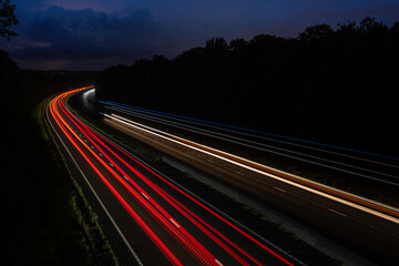 Long exposure white blue red and yellow light trails of cars and lorries driving on the motorway. A303 dual carriageway light trails at night - obrazy, fototapety, plakaty