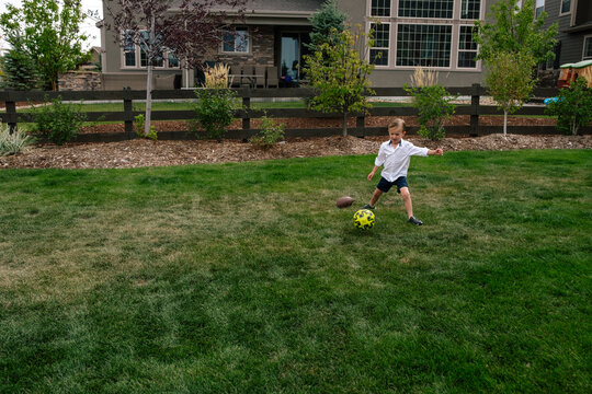 Little boy kicking a soccer ball in the back yard