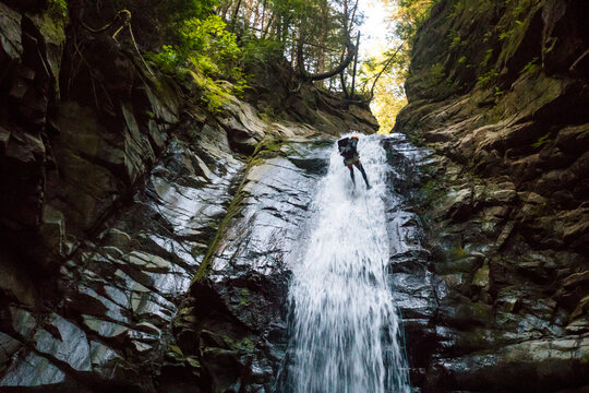 Low angle view of explorer rappelling down waterfall