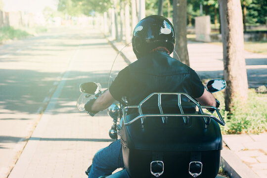 biker in leather vest riding his custom motorcycle
