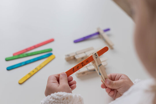 Child solves math examples with wooden sticks , didactic materials , Diy, home education. Mathematics for preschooler.