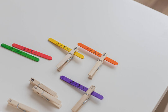 Child solves math examples with wooden sticks , didactic materials , Diy, home education. Mathematics for preschooler.