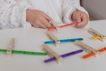 Child solves math examples with wooden sticks , didactic materials , Diy, home education. Mathematics for preschooler.