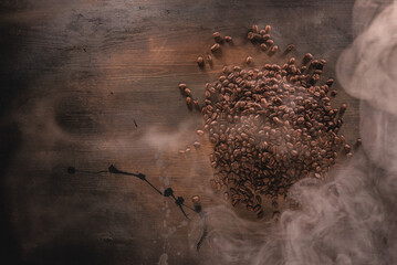 Pile of coffee beans on the old wooden table background.