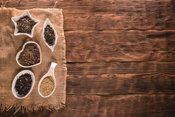 Various kinds of dried tea leaves on the brown wooden table background.
