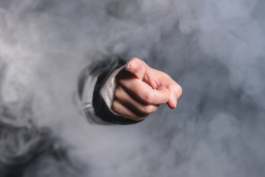 A person is showing ahead by her index finger through the smoke.