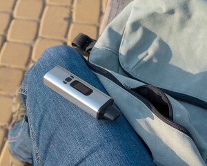 a portable herbal vaporizer lies on the leg in a man's jeans