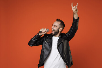 Funny young bearded man 20s wearing casual basic white t-shirt, black leather jacket standing sing...