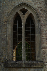 An old castle window seen from the outside of a turret with old arches and a narrow frame. Stone window with metal work.