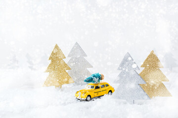 Toy car carrying christmas tree in a snow forest