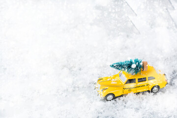 Toy car carrying christmas tree in a snow forest