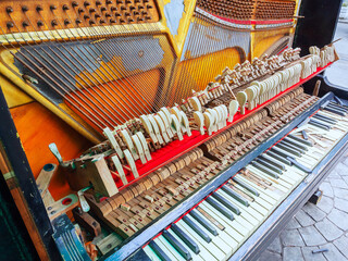 An old broken piano with a missing wall and broken keys