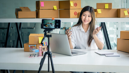 A young woman who is online on the phone to sell things and a computer placed in front of them with...