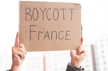 A man holds a cardboard poster with the inscription Boycott of France