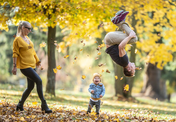 Dad doing backflip makes his son and wife laugh during a fun autumn day in teh nature