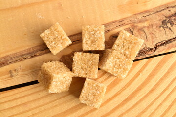 Several cubes of brown sugar, close-up, on a wooden table.