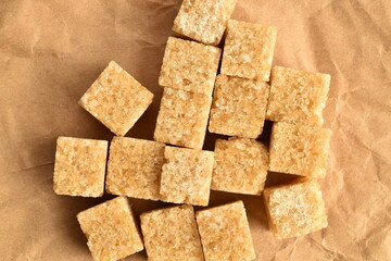 Several cubes of brown sugar, close-up, on brown paper.