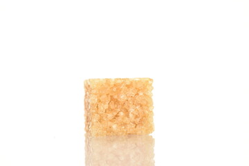 One brown sugar cubes, close-up, on a white background.