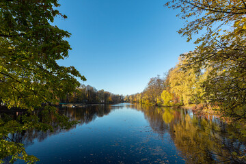 Fototapeta na wymiar Calm river flowing through the autumn park on Elagin Island, Saint Petersburg, Russia.
