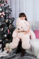 Girl with a big teddy bear in Christmas decorations