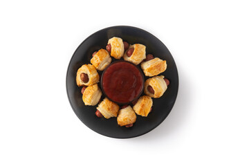 Pigs in blankets. Mini sausages wrapped in puff pastry with ketchup sauce isolated on white background