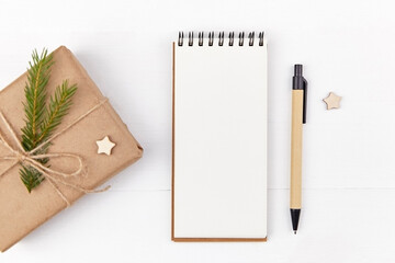 Christmas creative layout with gift box and blank notepad on white background.