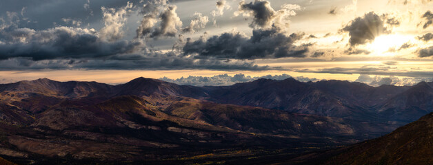 Naklejka na ściany i meble Aerial Panoramic View of Scenic Landscape and Mountains on a Cloudy Fall Season in Canadian Nature. Colorful Sunrise Sky Artistic Render. Taken in Tombstone Territorial Park, Yukon, Canada.