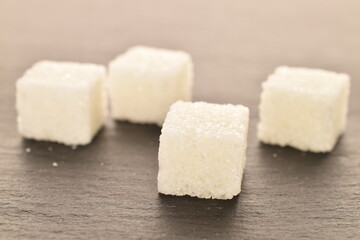 Several cubes of white sugar, close-up, on a slate board.