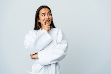 Young asian woman doing karate isolated on white background relaxed thinking about something looking at a copy space. © Asier