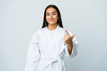 Young asian woman doing karate isolated on white background pointing with finger at you as if inviting come closer. © Asier