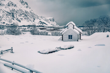 Dramatic morning scene after huge snowfall over polar circle. Snowy winter scene of Lofoten Islands. Small cemetery on Vestvagoy island, Norway, Europe. Vintage filtered.