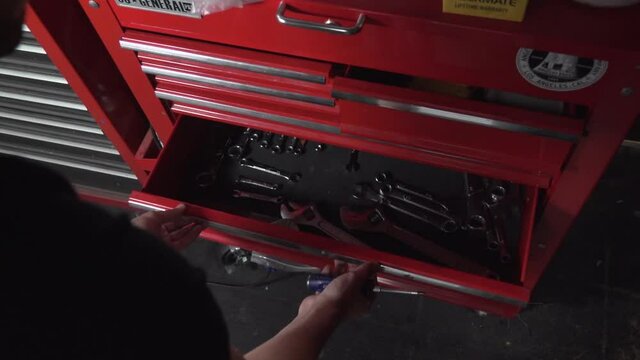 Male Opening a Giant Red Tool Cabinet a grabbing a Screwdriver and Wrench