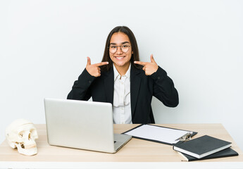 Young traumatologist asian woman isolated on white background smiles, pointing fingers at mouth.