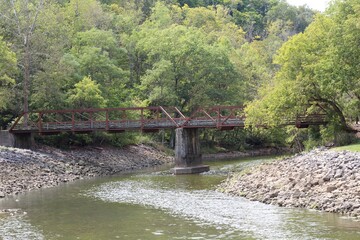 Obraz premium The bridge over the creek in the park on a sunny day.