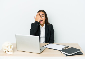 Young traumatologist asian woman isolated on white background having fun covering half of face with palm.