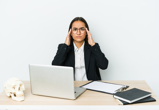 Young traumatologist asian woman isolated on white background focused on a task, keeping forefingers pointing head.