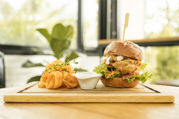 Tasty fired chicken with arugula and mayonnaise sauce served on wooden board, fired chicken Cheese Burger with Spicy Seasoned Curly Fries Ready to Eat
