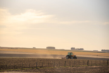 Fototapeta premium Agricultural tractor preparing field for sowing and background landscape of the pampa biome in Brazil