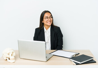 Young traumatologist asian woman isolated on white background looks aside smiling, cheerful and pleasant.
