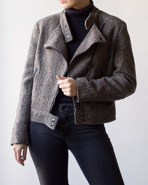 Woman wearing stylish outfit with black turtleneck, ramones jacket and black jeans isolated on white background. Copy space