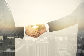 Multi exposure of handshake two businessmen on city skyline background, cooperation and coworking...
