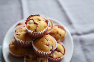 Heap of strawberry muffins on white plate over linen napkin
