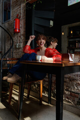 caucasian young woman curly hair, red shirt and jeans with cup cake and cup of coffee