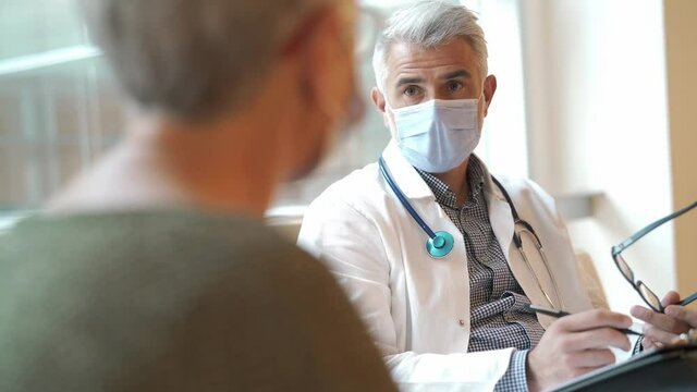 Doctor with face mask listening to patient in office, 19-ncov pandemic